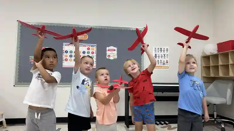 Children holding model airplanes during a group activity