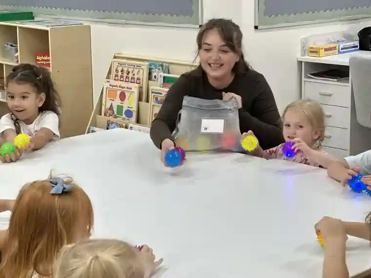 A smiling teacher leading a hands-on classroom activity with children