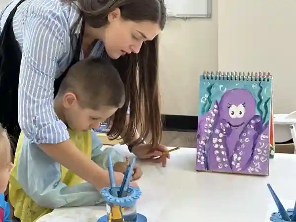 A teacher helping a child during an art activity